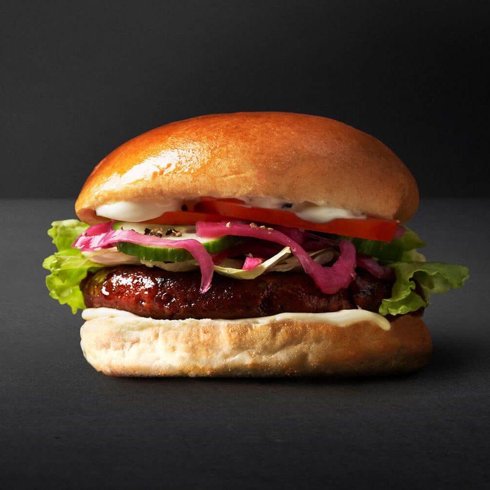 En saftig kødfri burger med en plantebaseret bøf, toppet med syltede rødløg og serveret i en blød bolle